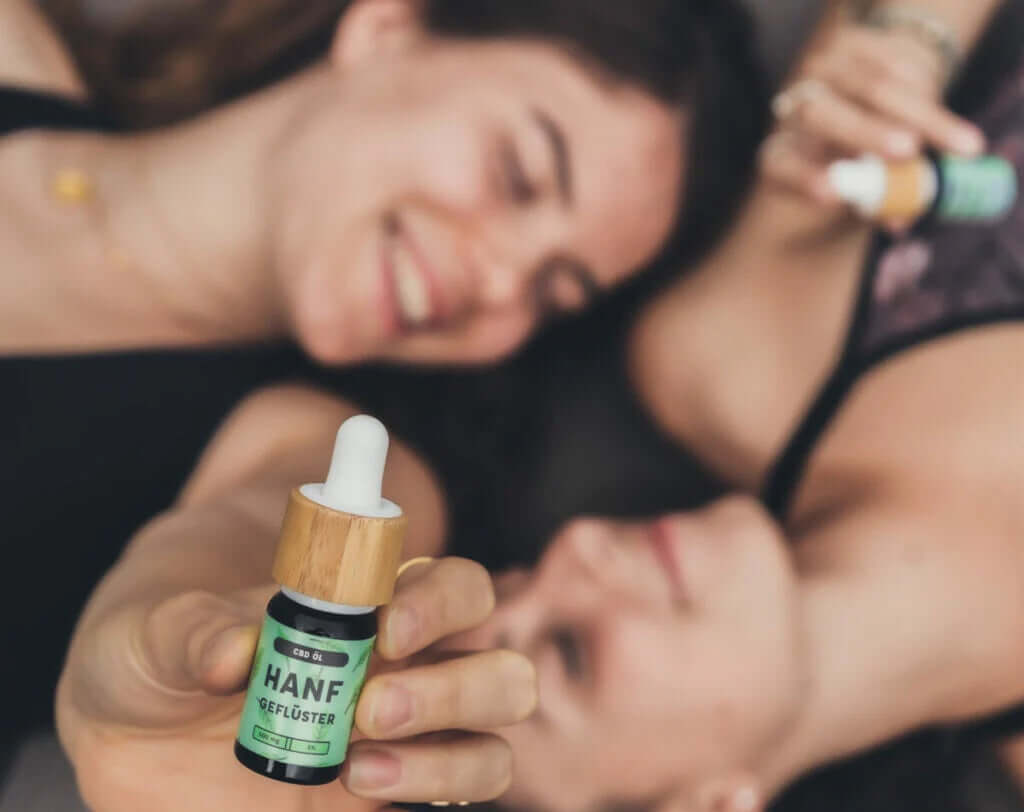 Zwei lächelnde Frauen halten Hanfgeflüster CBD Öle in den Händen