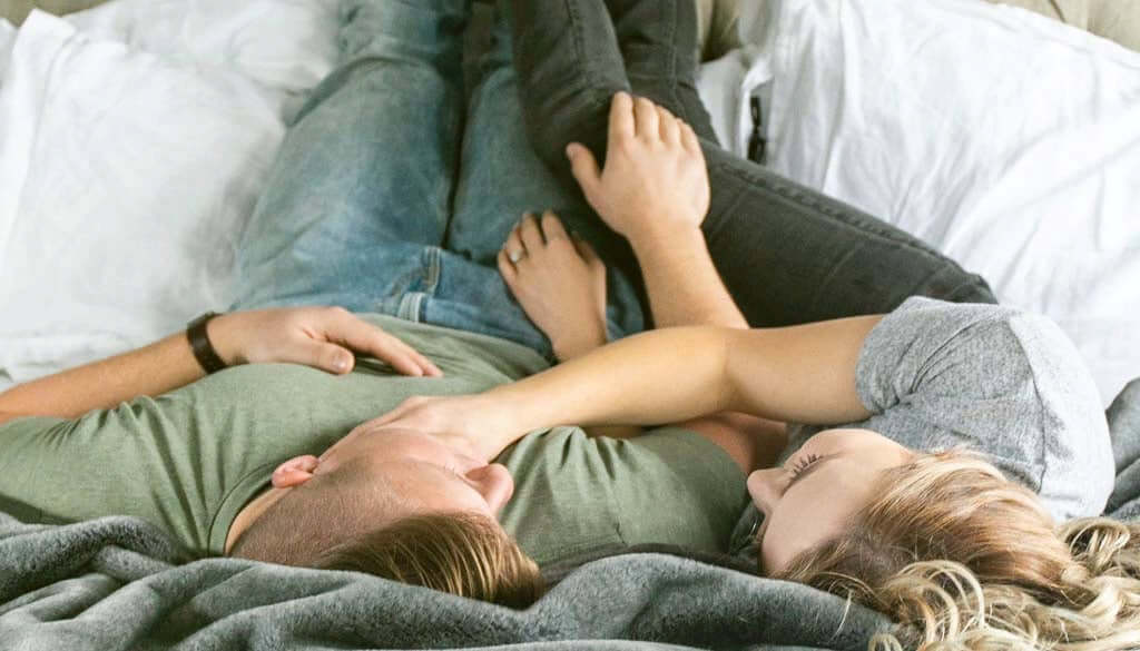Mann und Frau liegen kuschelnd im Bett