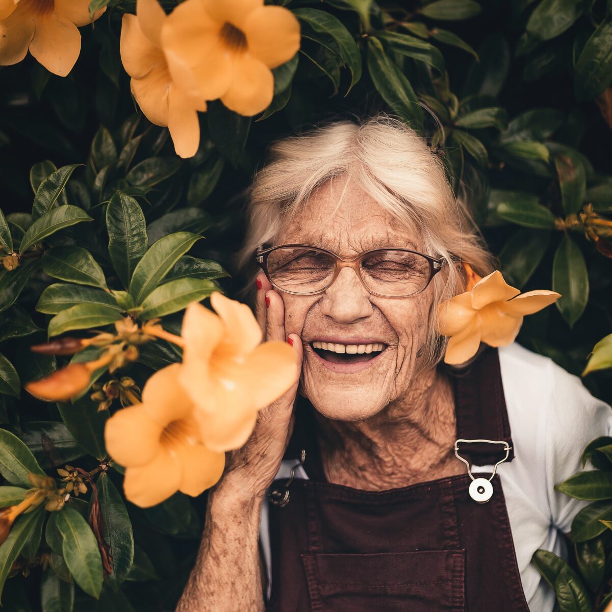 Alte lachende Frau mit Blumen